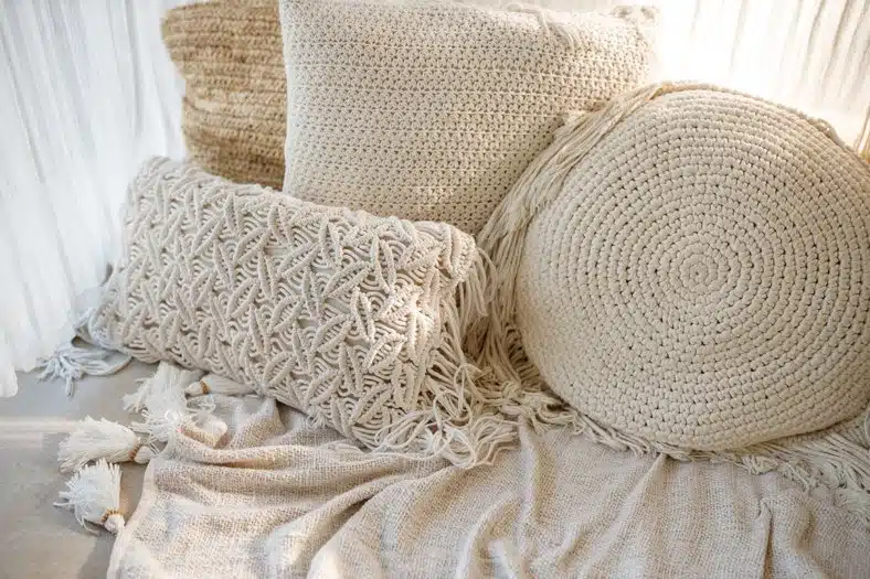 White macrame pillows and knit blanket on the sofa. Scandinavian cozy home, details interior
