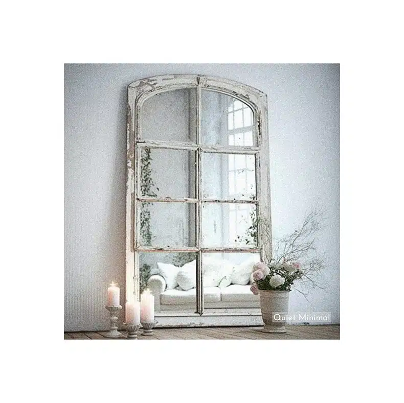 A mirror adorned with candles and flowers, repurposed from an old vintage window.