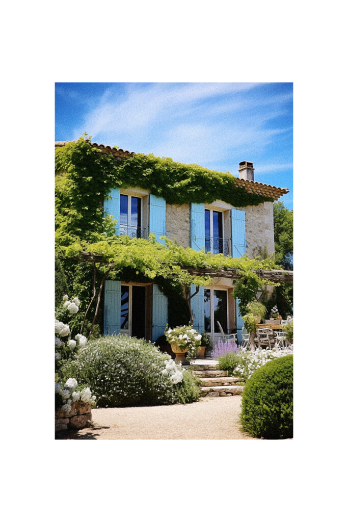 A French Country Cottage with blue shutters and ivy growing on it.