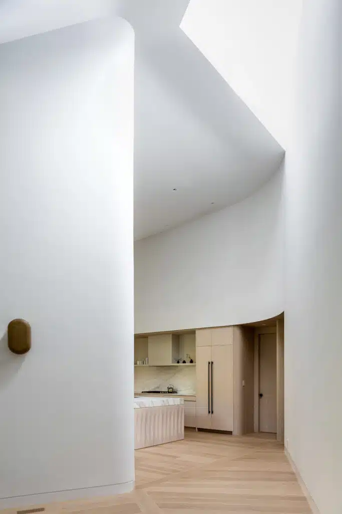 A white kitchen with wooden floors and a skylight.