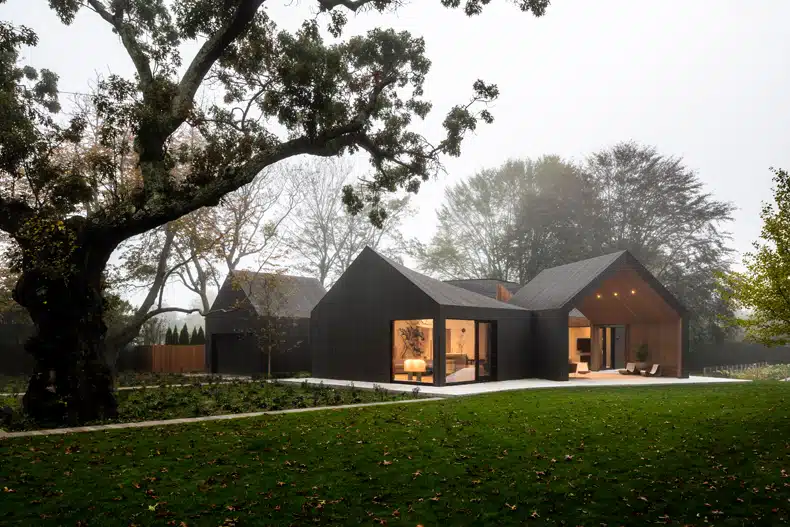 A black house with a tree in the background.
