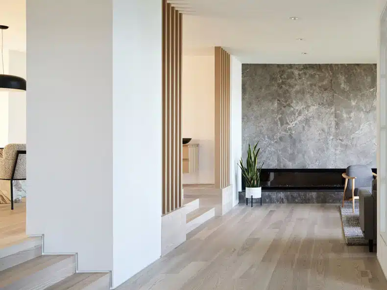A modern living room with wood floors and a fireplace, elegantly designed by BLA Design Group in Rockridge House.