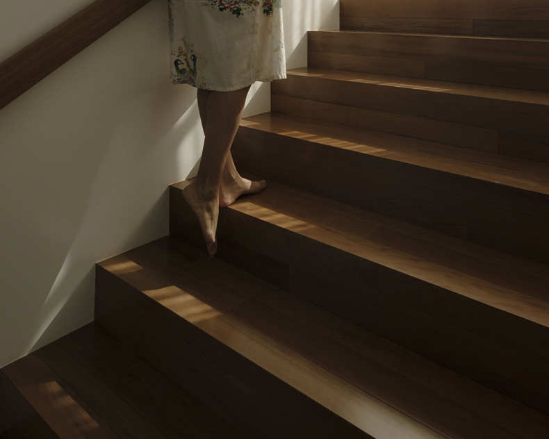 A woman's feet on a wooden staircase.