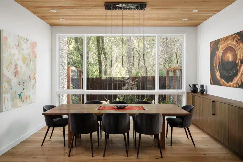 A dining room with a wooden ceiling and black chairs.