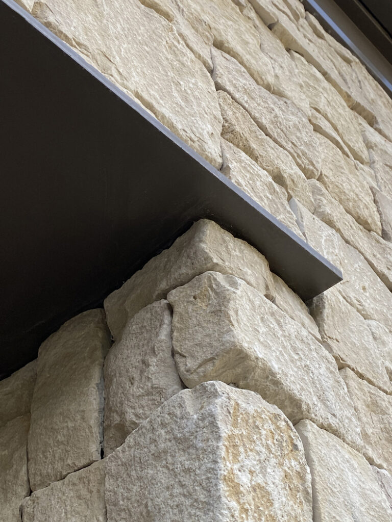A close up of a stone wall with a metal shelf.