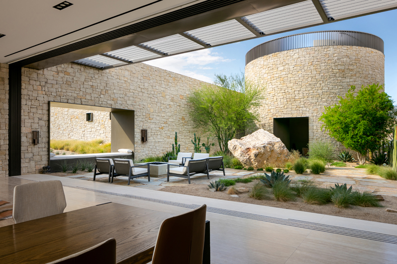 A modern home with a stone wall in the backyard.