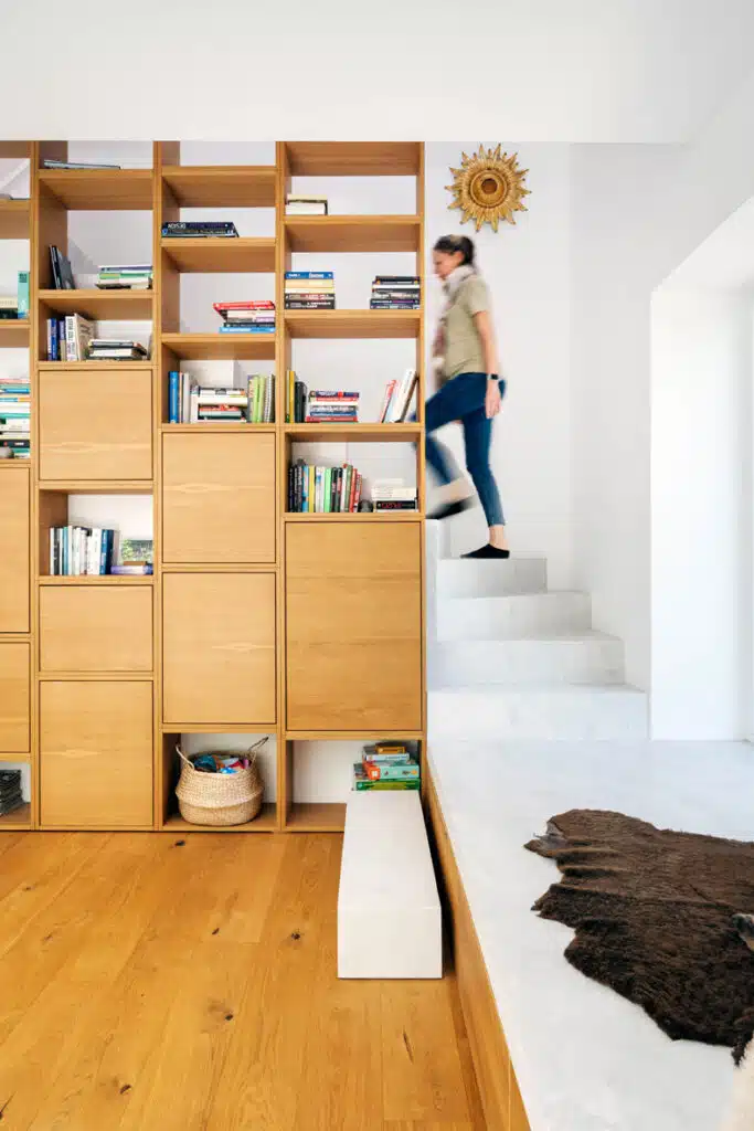 A woman is walking up a staircase in a room with bookshelves.
