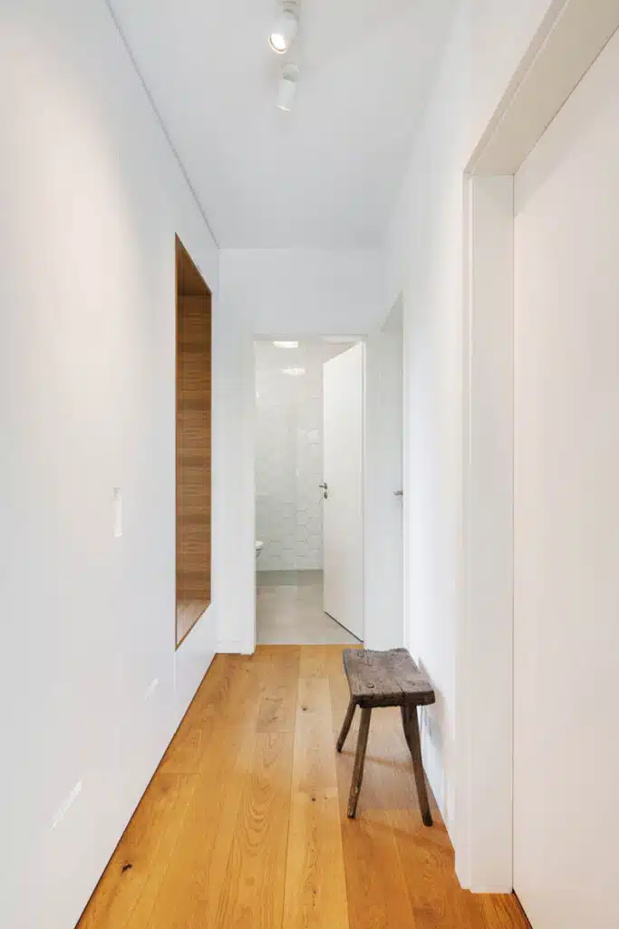 A hallway with wooden floors and white walls.