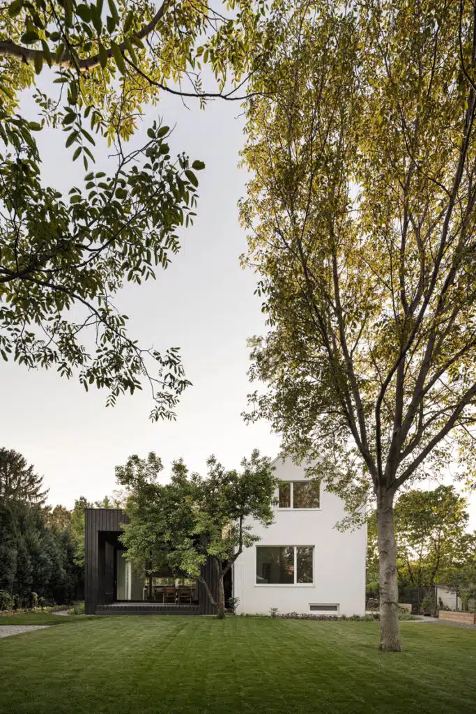 A modern house surrounded by trees and grass.