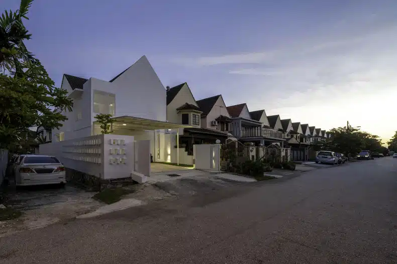 A white house at dusk on a street.