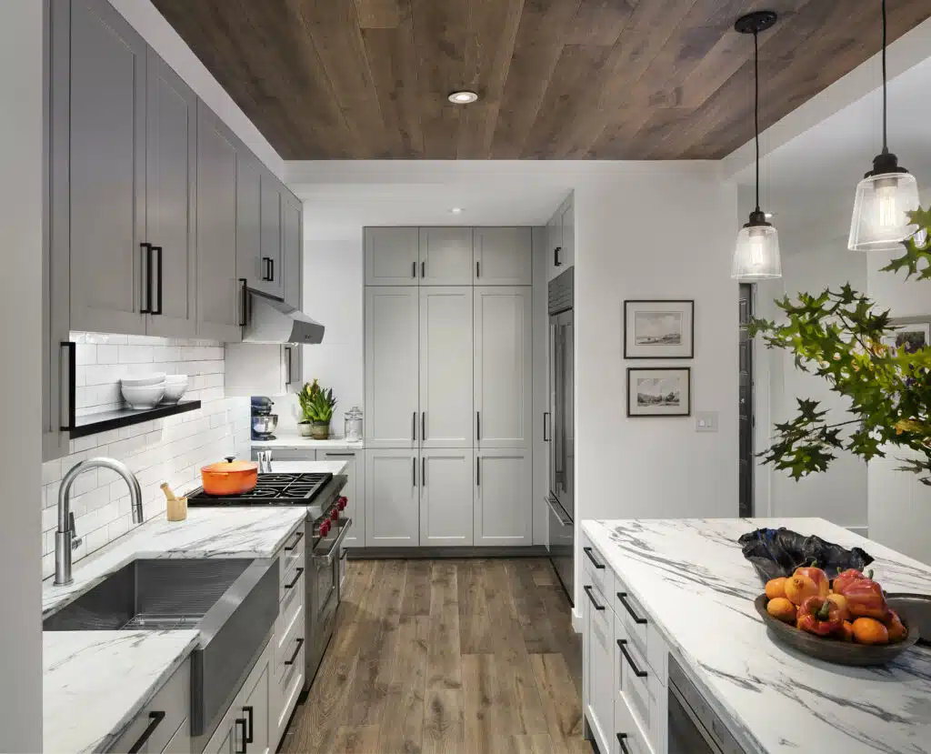 A kitchen with white cabinets and a wooden ceiling.