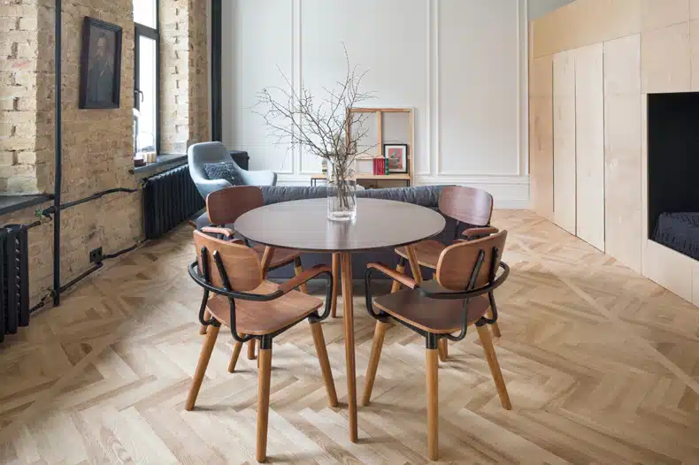 A dining table and chairs in a room with wooden floors, designed by Studio Martin's for Smart 60 Apartment.