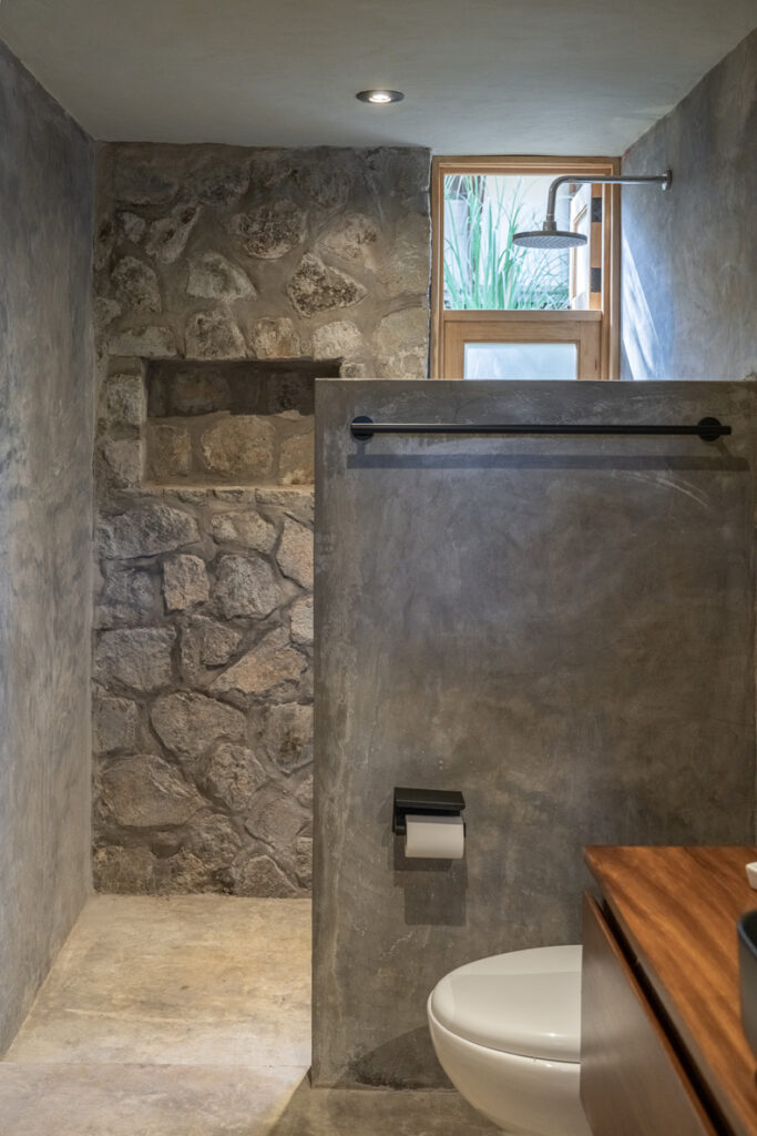 Petraia House features a bathroom adorned with a stunning stone wall and a modern toilet.
