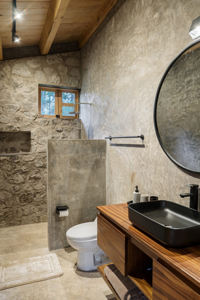 Petraia House By Argdl: A bathroom with a toilet, sink, and mirror.