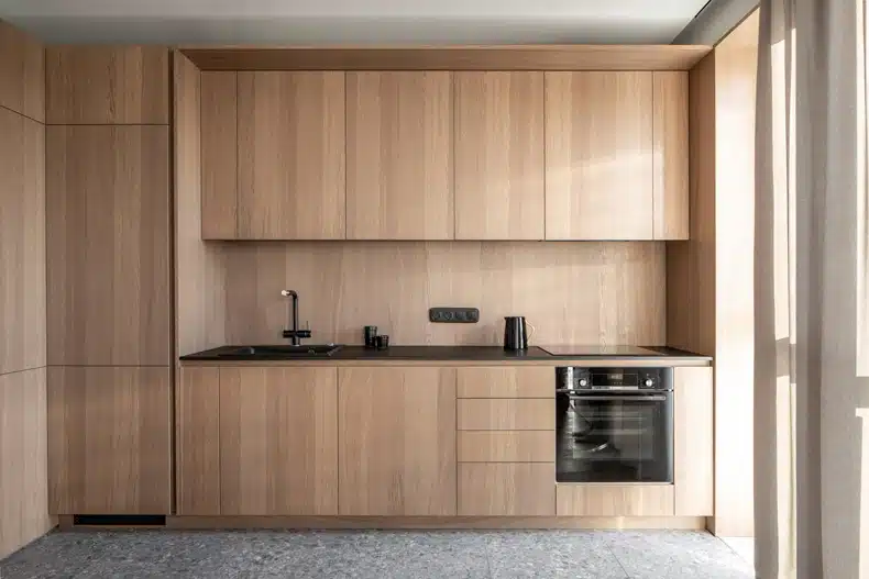 Zaricnyy Apartment By Kouple features a kitchen with wooden cabinets and a sink.