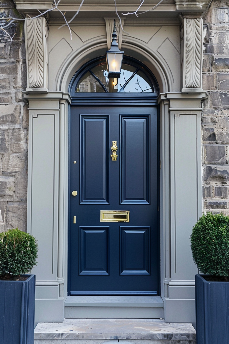 Classic navy blue front door with brass fixtures, flanked by two potted plants, and an overhead arching lantern.