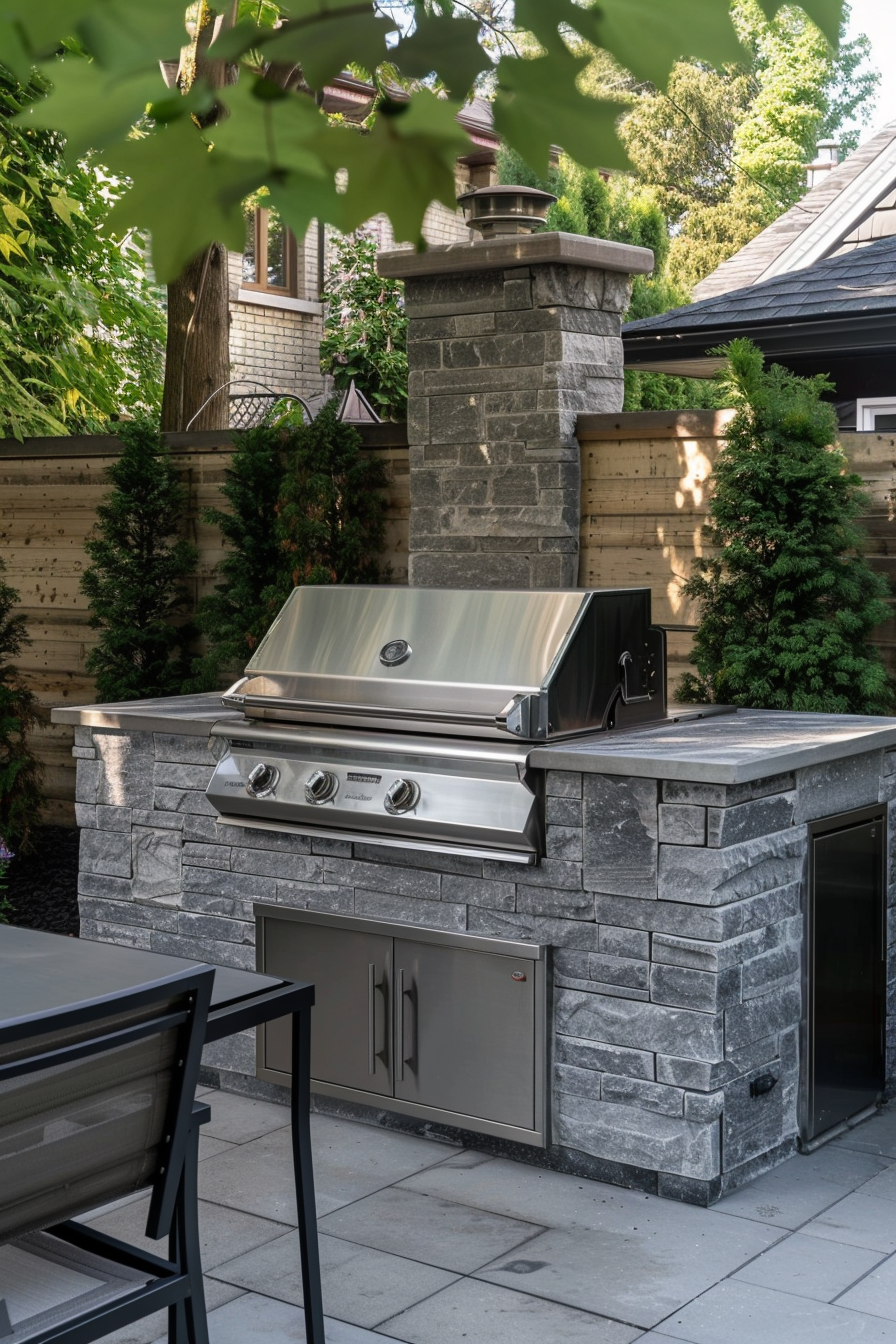ALT: An outdoor stainless steel grill built into a stone island in a backyard patio setting, surrounded by lush greenery.