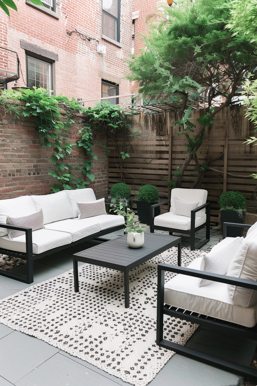 Cozy outdoor patio area with a modern sofa set, patterned rug, and greenery against a brick wall background.