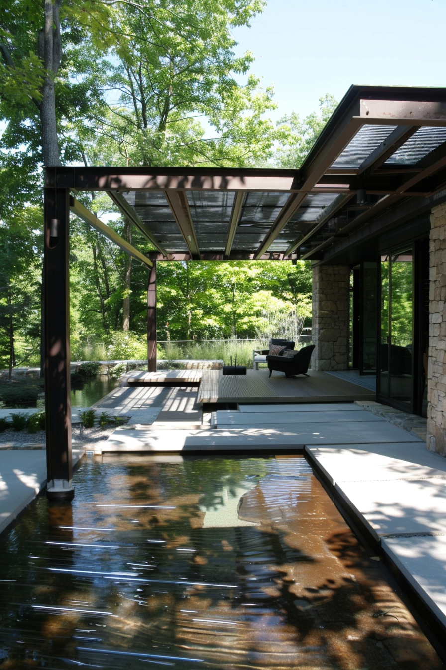 Modern house with a sleek patio over a reflective pond, surrounded by trees under a clear sky.