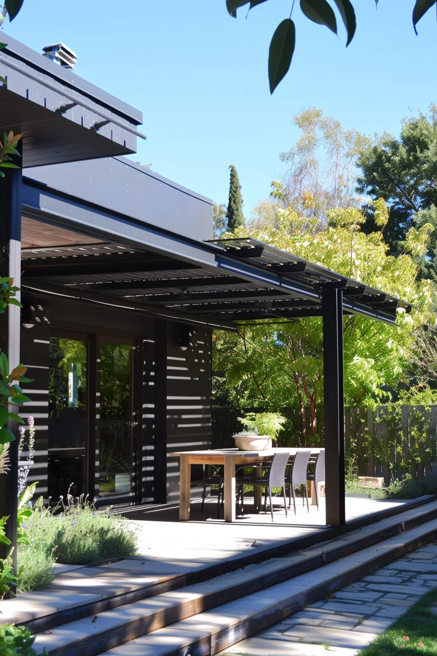 Modern outdoor patio with wooden dining table and chairs under a pergola, surrounded by green garden and trees.