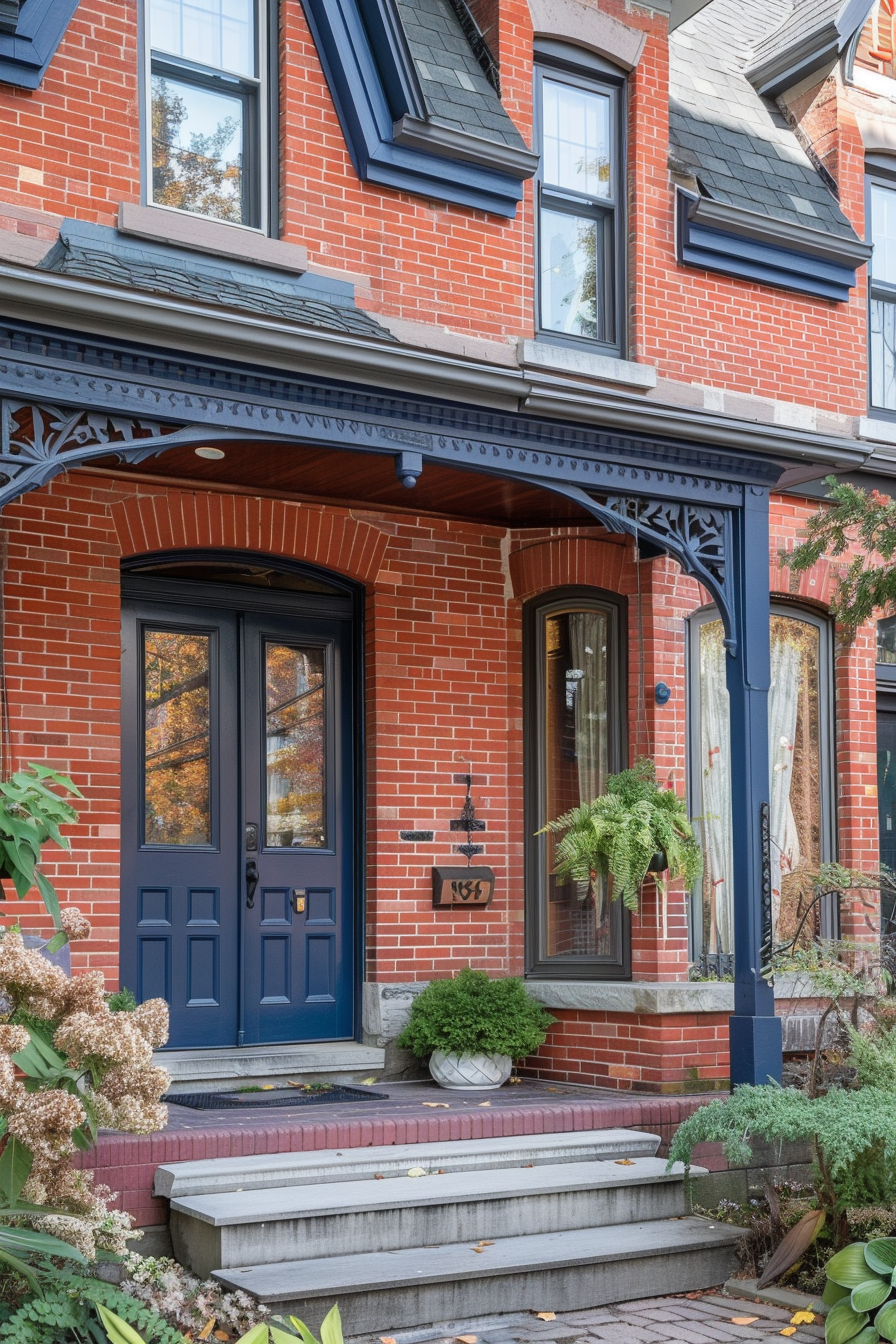 Alt text: Traditional brick house with a blue front door, matching trim, and decorative iron porch detailing, complemented by potted plants.