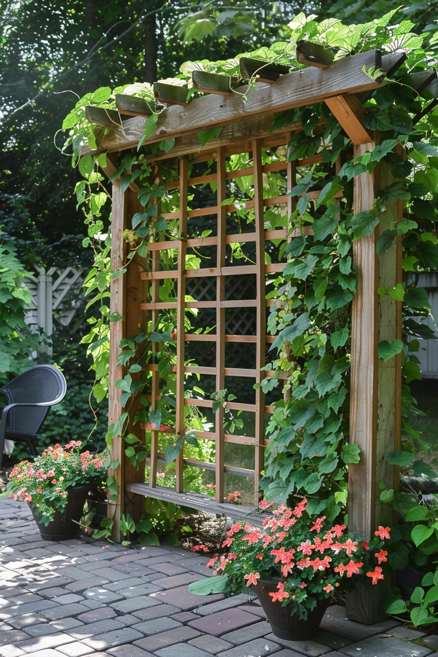 A wooden garden trellis covered with climbing green vines and surrounded by blooming red flowers, set on a brick patio.