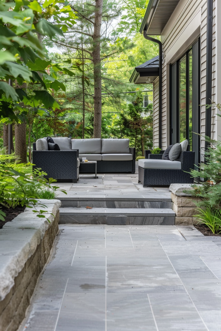 Outdoor patio area with modern wicker furniture set along a stone pathway surrounded by greenery.
