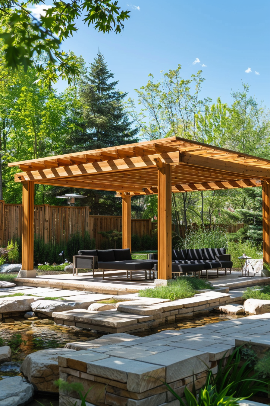 Wooden pergola over patio furniture in a lush garden with stone path and small pond on a sunny day.