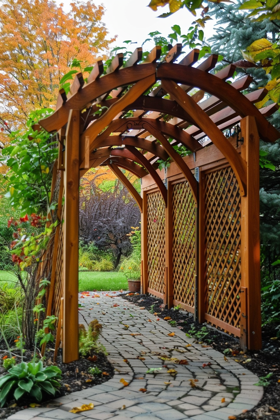 Wooden garden archway over a curved stone path with scattered leaves, surrounded by greenery and autumn trees.