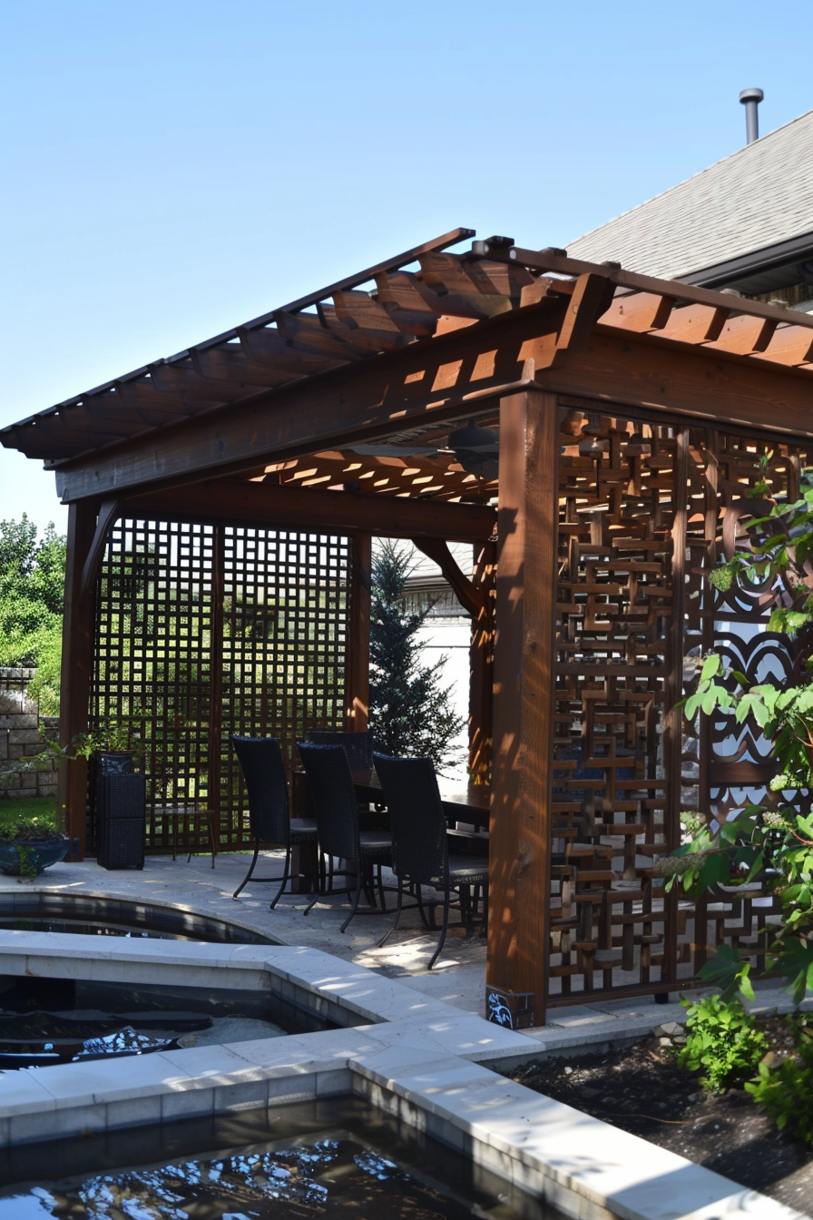 Outdoor wooden pergola with a dining area and a lattice wall overlooking a tranquil garden with a small pond.
