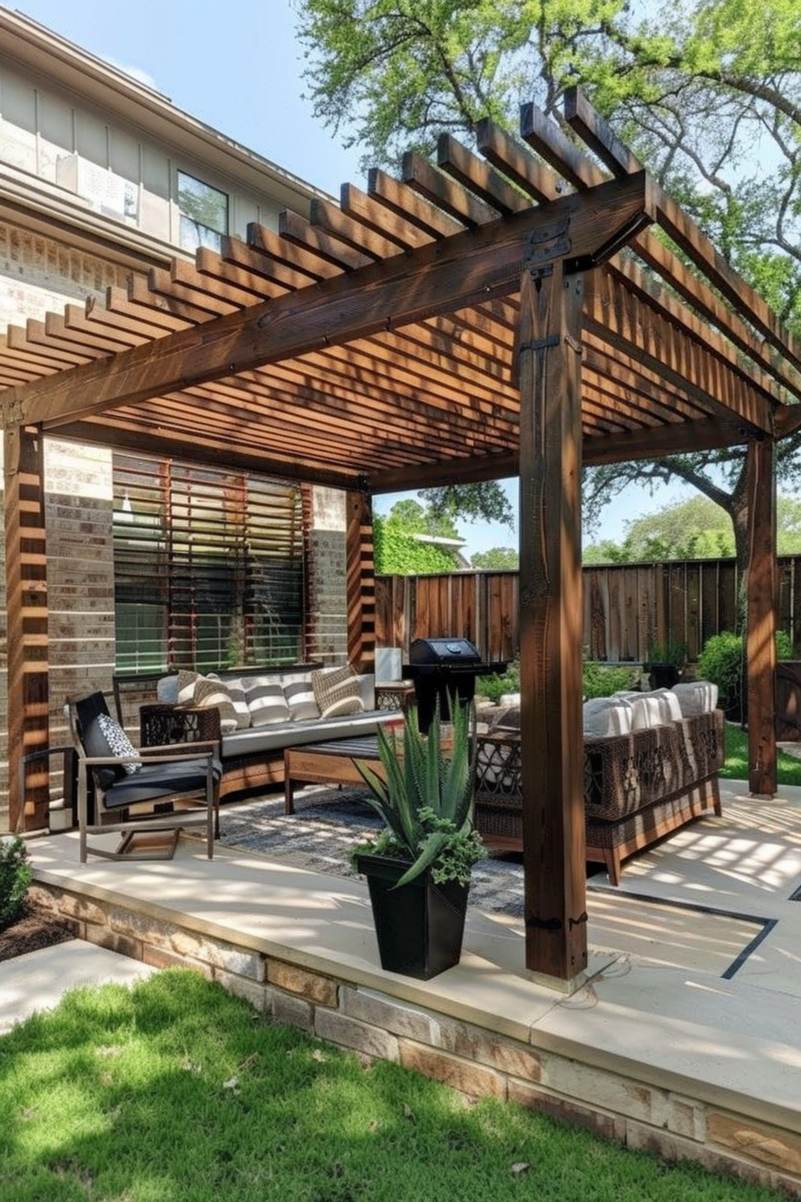 Wooden pergola over a cozy outdoor patio with furniture and potted plants, near a brick house.