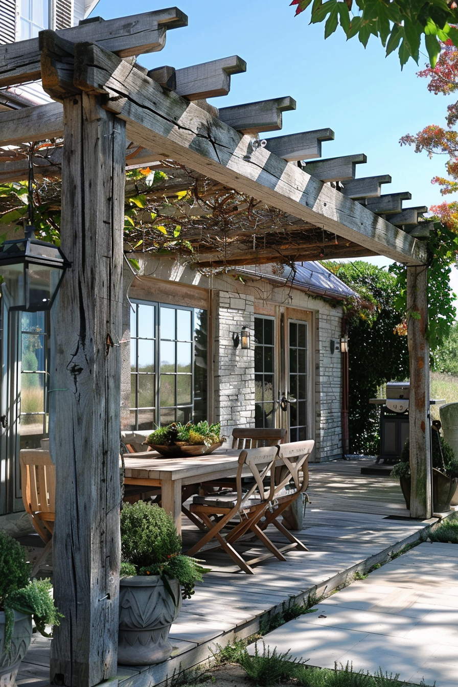 Rustic outdoor wooden pergola with trailing vines over a dining table, complementing a stone cottage with large windows.