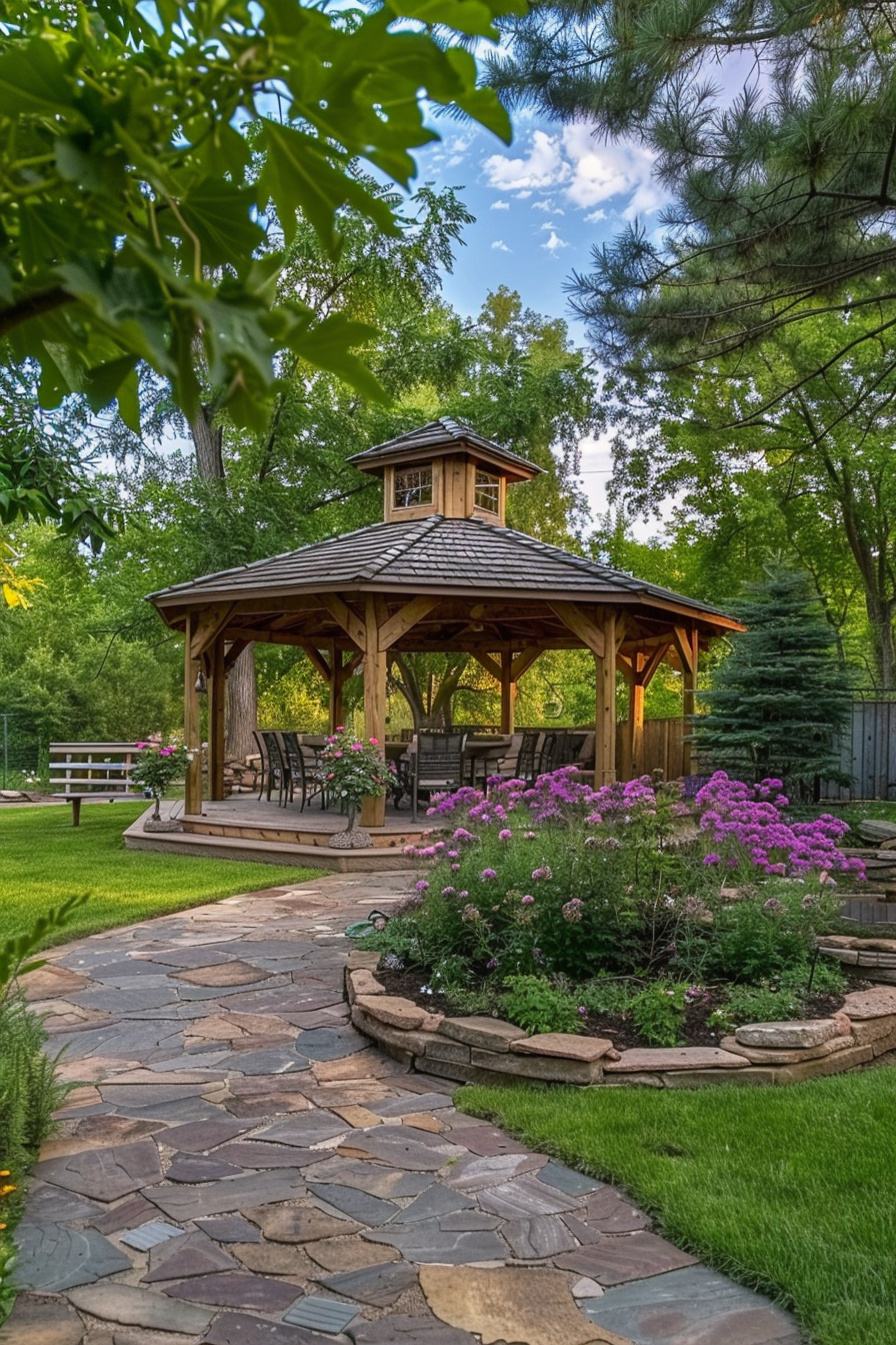 ALT: A picturesque garden gazebo surrounded by lush greenery, blooming purple flowers, and a winding stone path under a blue sky with fluffy clouds.