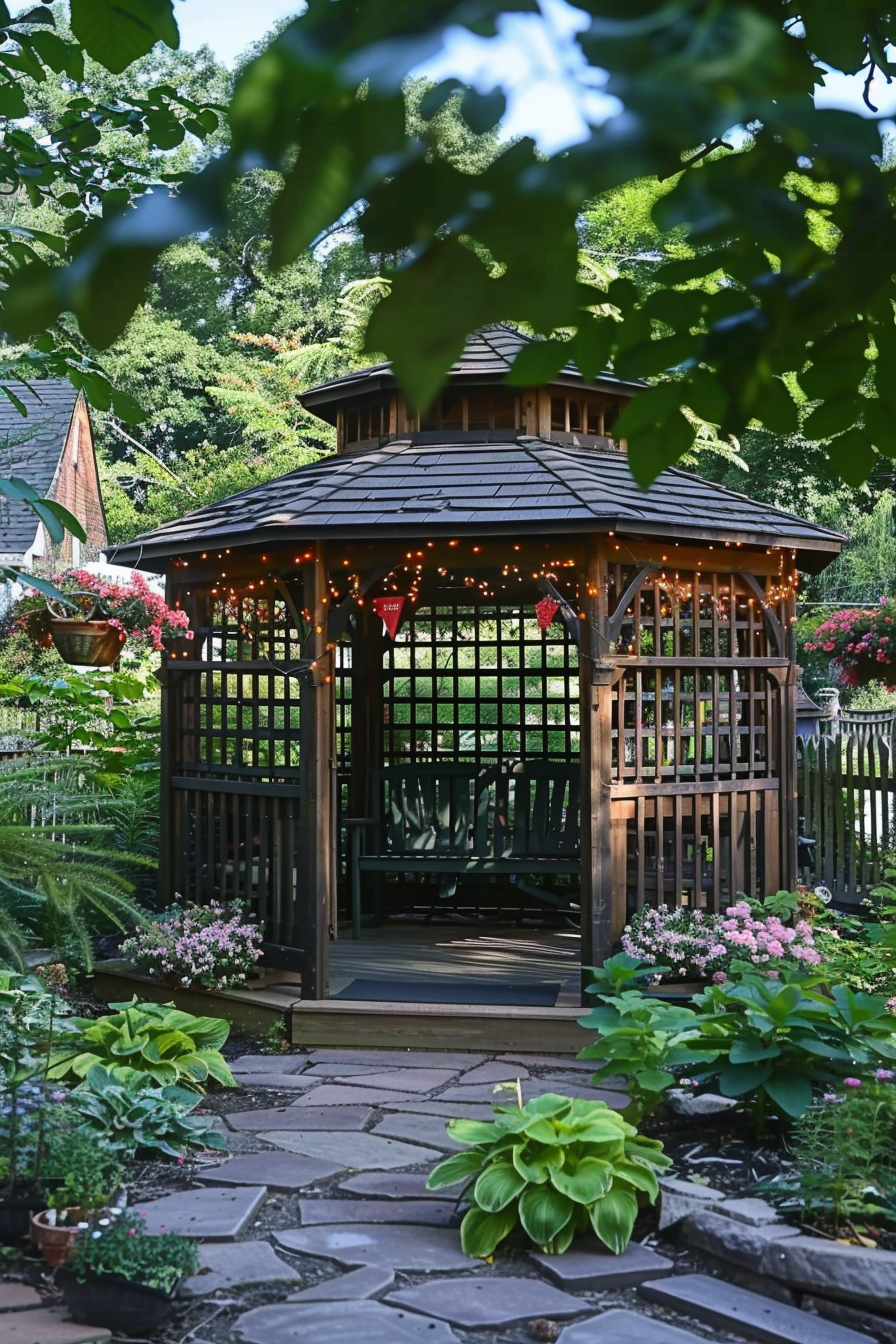 A charming wooden gazebo adorned with string lights, nestled in a lush garden with flowering plants and a stone pathway.