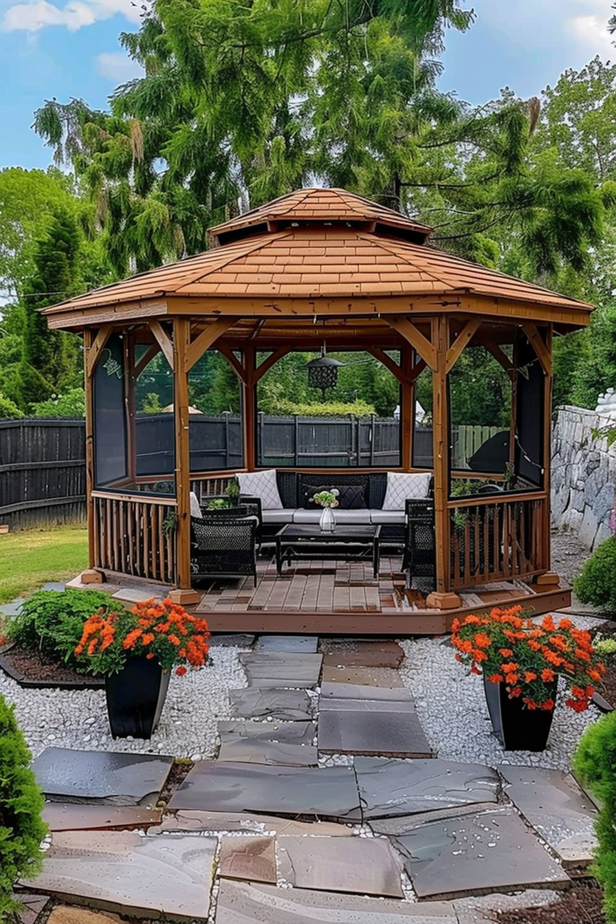 Wooden gazebo with screens, outdoor seating, and hanging lantern, on a stone pathway surrounded by greenery and flowering plants.
