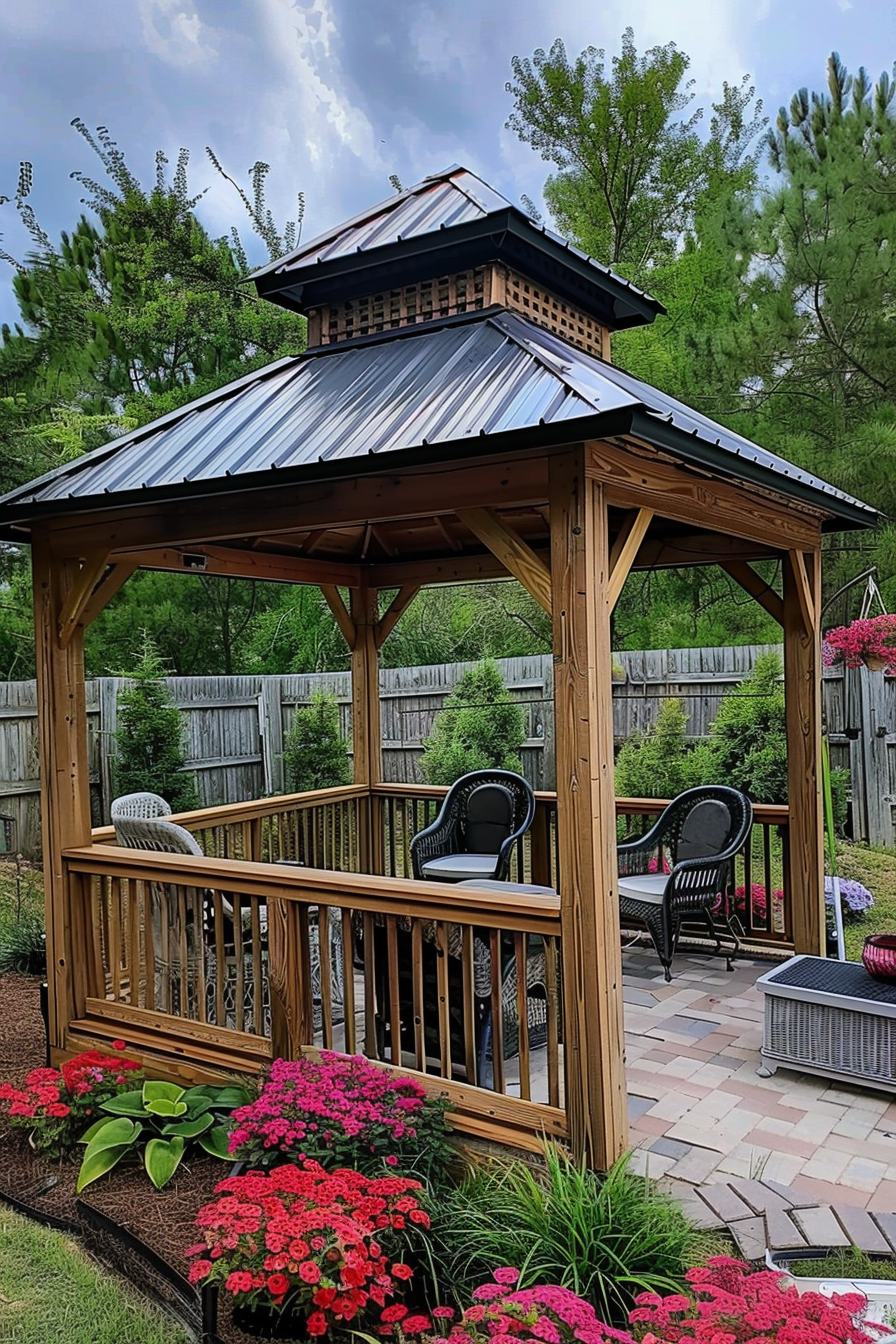 Wooden gazebo with a metal roof in a garden, surrounded by lush flowering plants and outdoor seating.