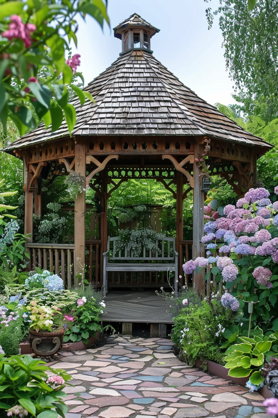 Wooden gazebo in a lush garden with hydrangeas, a stone pathway, and green foliage.