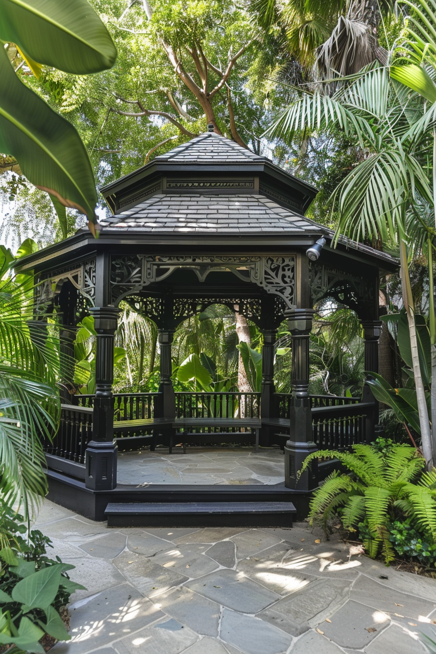 An elegant black wooden gazebo surrounded by lush greenery and tropical plants in a serene garden setting.