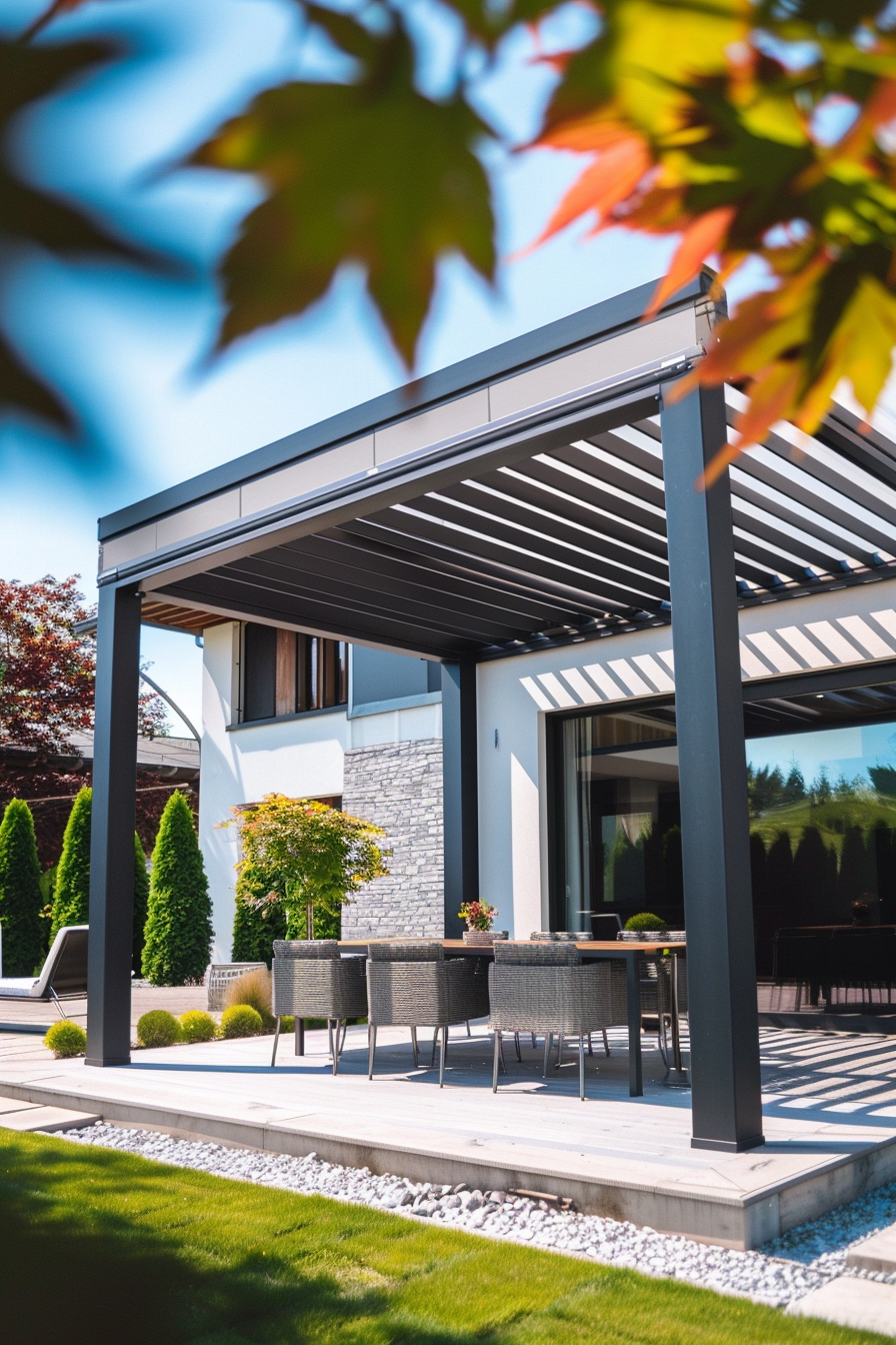 Modern patio with a pergola, outdoor furniture, on a sunny day framed by autumn leaves in the foreground.