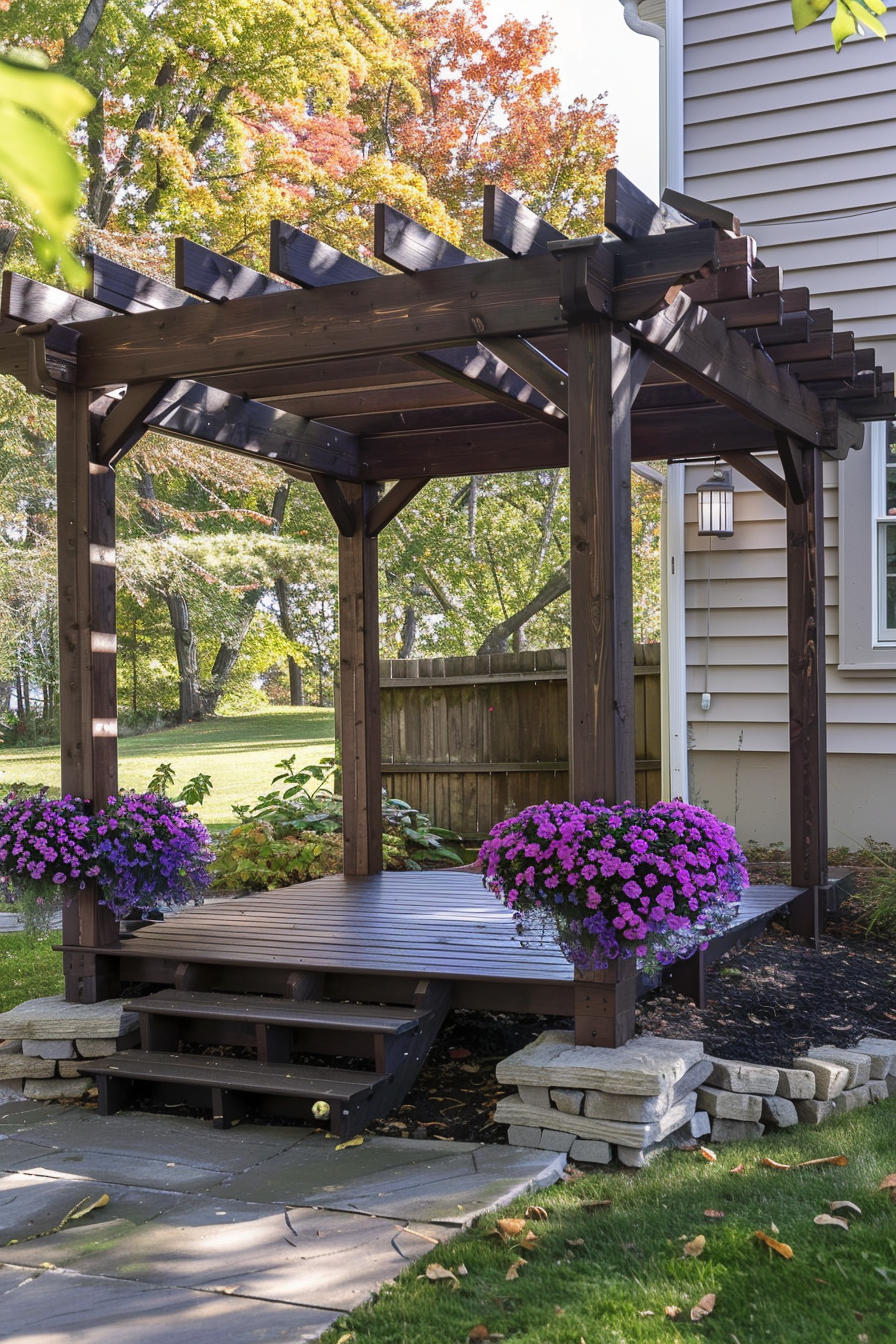 A wooden pergola on a deck adorned with vibrant purple flowers, set against an autumn backdrop with tree foliage changing color.