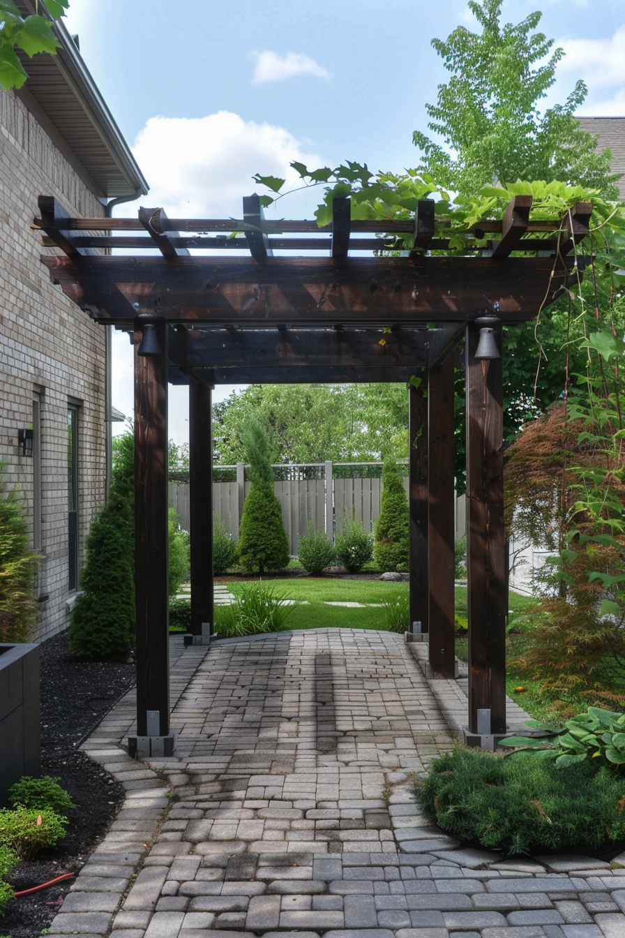 Wooden pergola over a cobblestone pathway in a well-manicured garden with greenery and a clear sky.