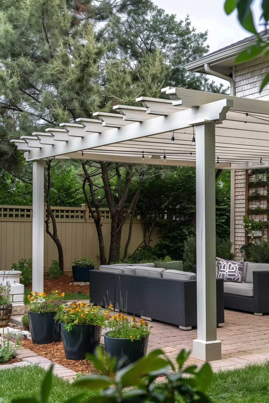 ALT: A cozy backyard patio with a modern pergola, outdoor wicker furniture, potted flowers, and a backdrop of trees and a privacy fence.
