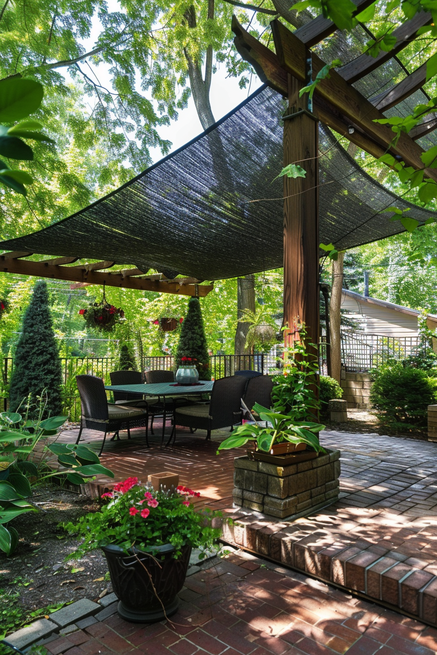 A shaded patio area with a dining set, surrounded by greenery and protected by a black overhead sunshade.