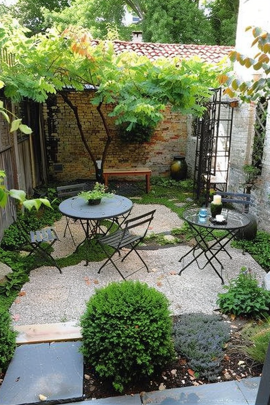Quaint garden patio with a round table, chairs, and lush greenery against exposed brick walls, creating an intimate outdoor space.