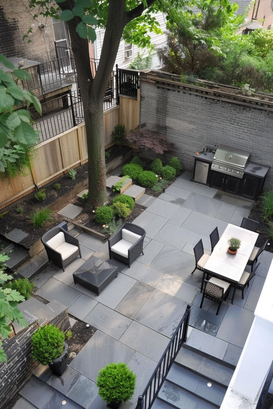 An overhead view of a cozy backyard patio with furniture, built-in grill, neat garden beds, and modern paving.