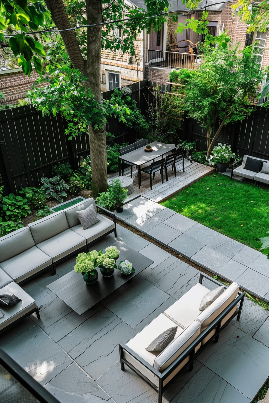 Modern backyard patio with outdoor furniture, lush greenery, and stone paving on a sunny day.