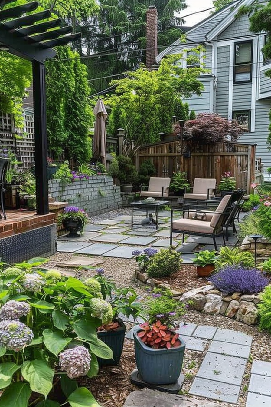 A cozy backyard garden with a seating area, stone pathways, lush greenery, and flowering plants in pots and flowerbeds.