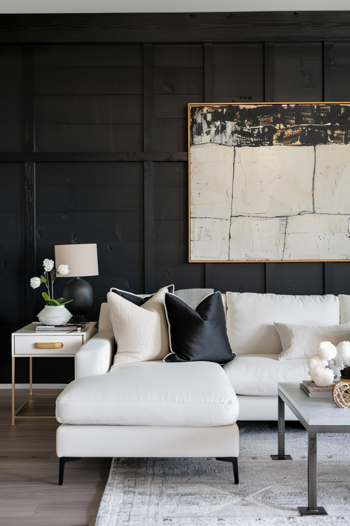 A stylish living room with a white couch, black and white pillows, a dark paneled wall, and abstract art.