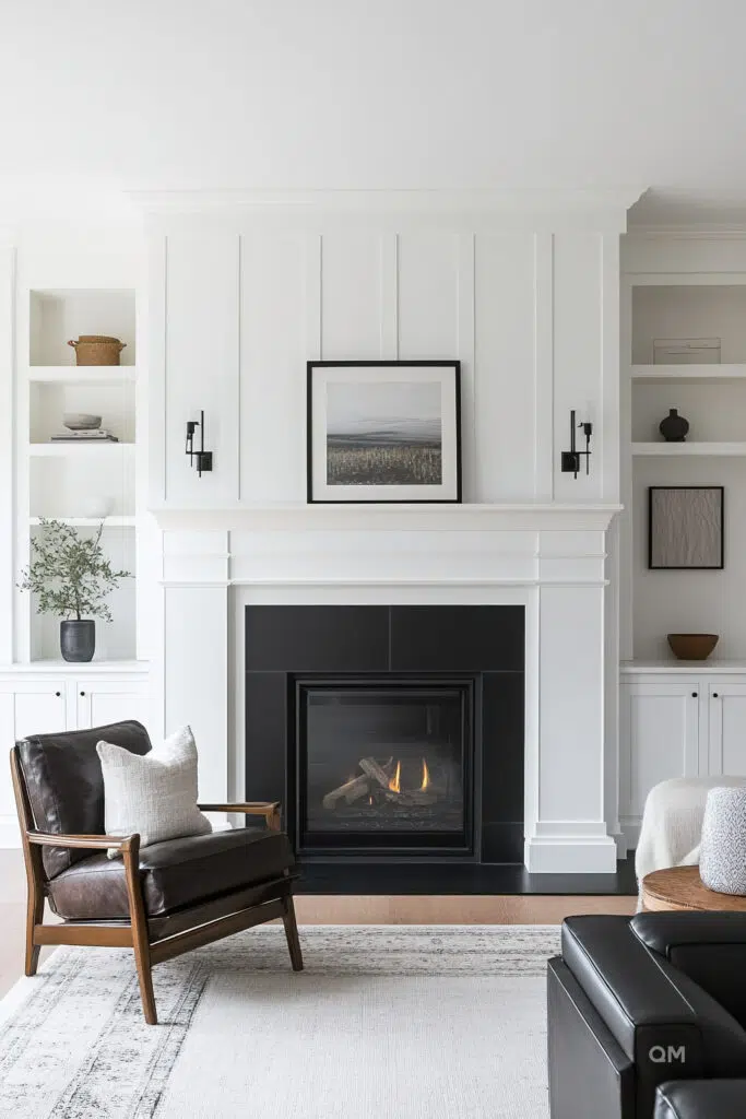 Elegant living room with a lit fireplace, white built-in shelves, a framed landscape photo above the mantle and stylish leather chair.