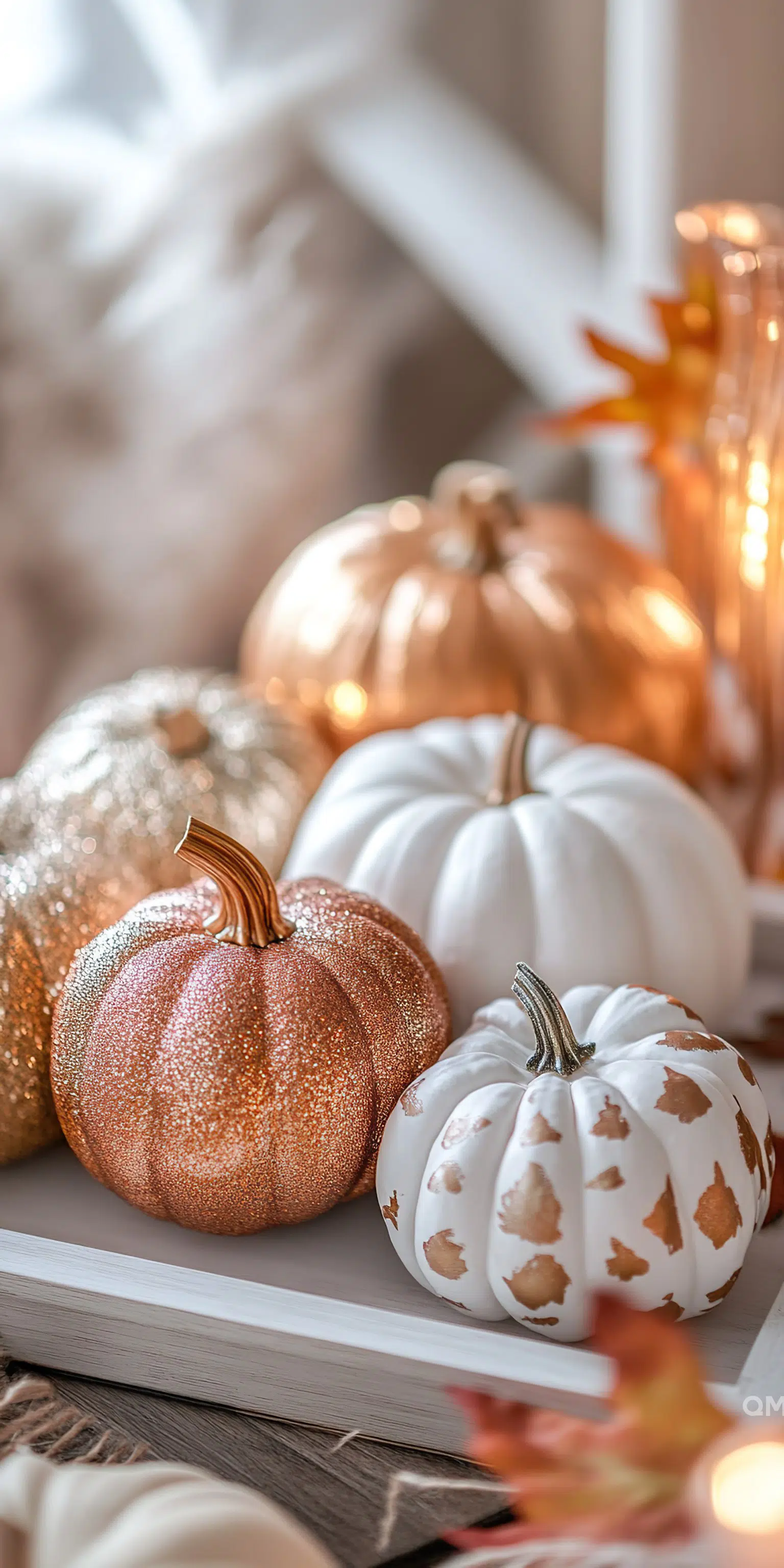 Decorative glittering and white pumpkins on a book with warm, cozy lighting, evoking an autumnal atmosphere.